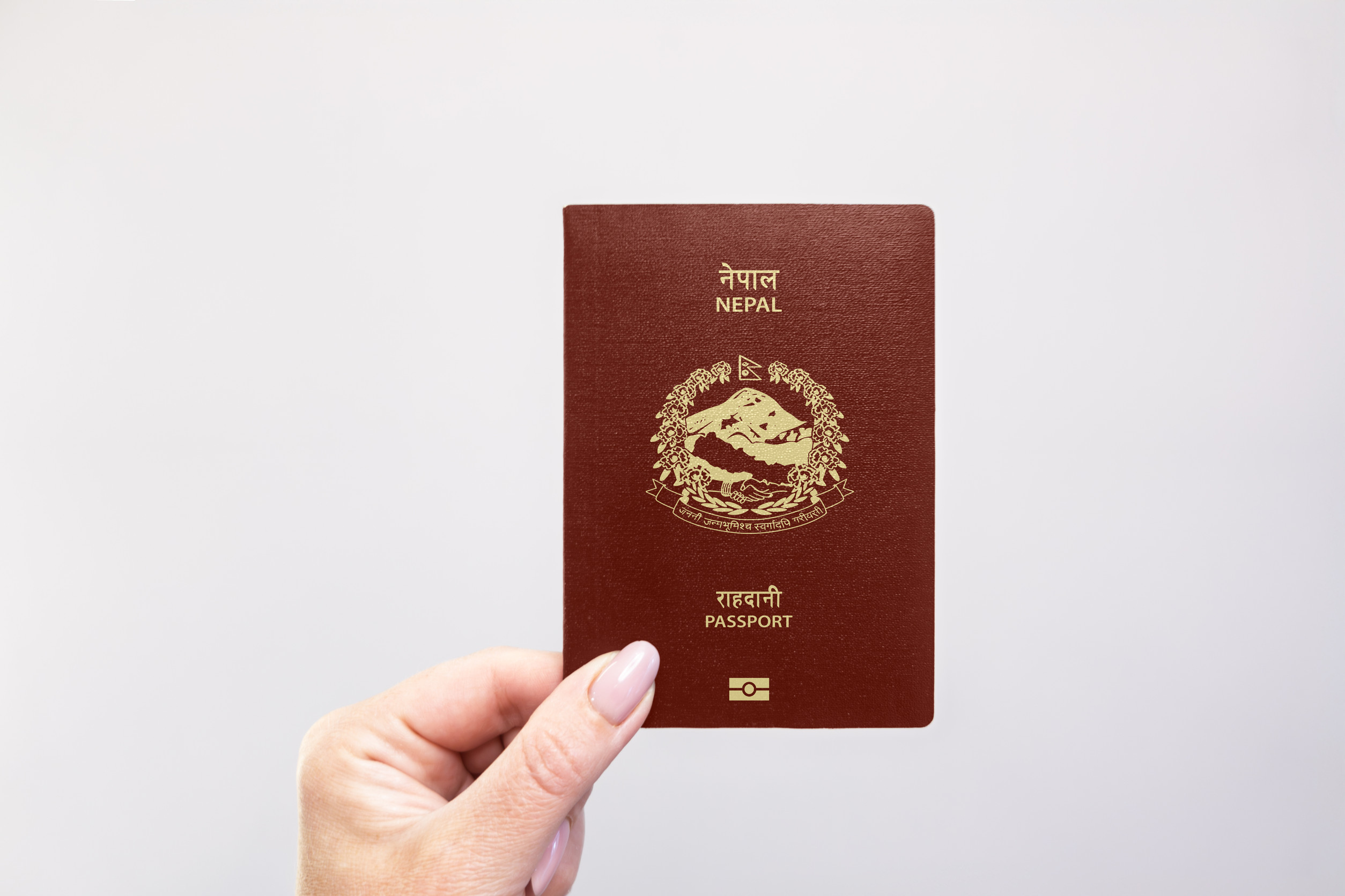 Hand holding Nepal maroon passport